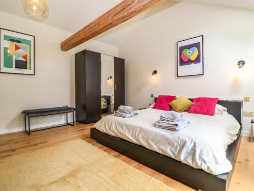um quarto com uma grande cama branca com almofadas vermelhas em The Cart Lodge at Grove Barn em Eye
