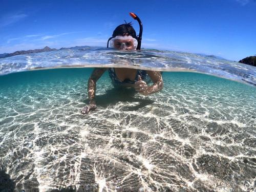 a person in the water with a surfboard at Angel Island Eco Resort in Labuan Bajo
