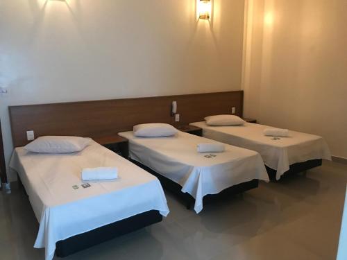 two beds in a hospital room with white sheets at Hotel Novo Apúlia in Sao Paulo