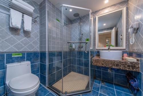 W wyłożonej niebieskimi kafelkami łazience znajduje się toaleta i umywalka. w obiekcie Morninginn, Zhenyu Plaza w mieście Shaoyang County