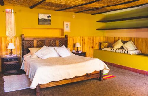 a bedroom with a large bed and a yellow wall at Hotel Finca el Recreo in Guasca