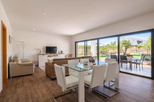 a dining room and living room with a table and chairs at Casa do Pomar, Piscina Privada, Prainha Alvor! in Alvor