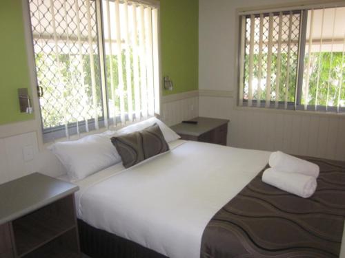a bedroom with a large white bed with two windows at Reflections Moonee Beach - Holiday Park in Moonee Beach