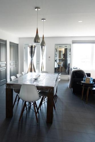 a dining room with a wooden table and white chairs at Les Chalets Baie Cascouia in Lac Kénogami