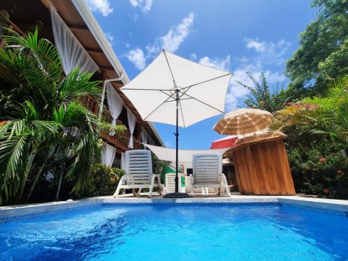 uma piscina com duas cadeiras e um guarda-sol e uma mesa e duas cadeiras em BellaVista Suites By Villas Verdes - Samara Beach em Sámara