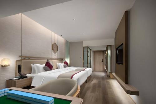 長沙市にあるMorning Hotel, Changsha Guihuaping Metro Stationのベッド2台とソファが備わるホテルルームです。