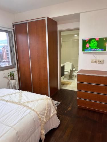 a bedroom with a bed and a bathroom with a tv at Depto cálido Balcarce in Balcarce