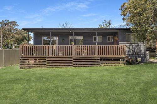 a house with a wooden fence and a yard at Corinya Cottage By Experience Jervis Bay in Worrowing Heights