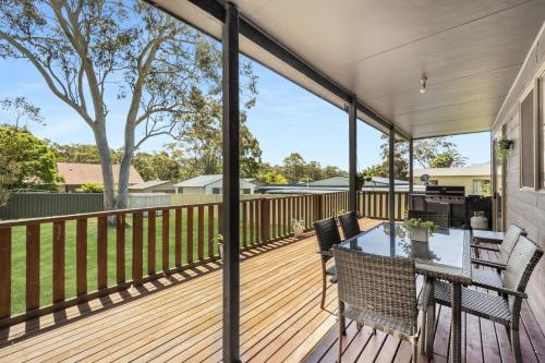 a patio with a table and chairs on a deck at Corinya Cottage By Experience Jervis Bay in Worrowing Heights