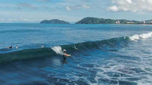a person riding a wave on a surfboard in the ocean at Surf Synergy All-Inclusive Surf and Wellness Retreat in Jacó