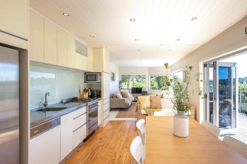 uma cozinha e sala de estar com uma mesa e um sofá em Tawa Cottage - Coast & Country em Oneroa