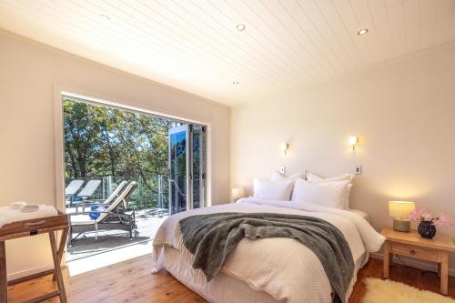 um quarto com uma cama e uma grande janela em Tawa Cottage - Coast & Country em Oneroa