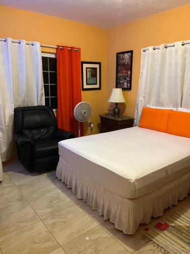 a bedroom with a large bed and a chair at Cool Breeze Mobay in Montego Bay