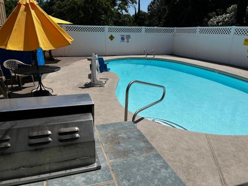 a swimming pool with a table and an umbrella at Super 8 by Wyndham Red Bluff in Red Bluff