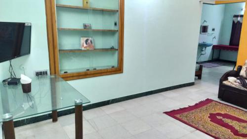 a living room with a glass table and a mirror at Acharyaa Homestay in Tiruchchirāppalli