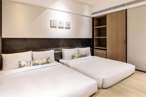 two beds in a hotel room with white at Hsin Hotel in Chiayi City