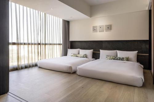 two beds in a room with a large window at Hsin Hotel in Chiayi City
