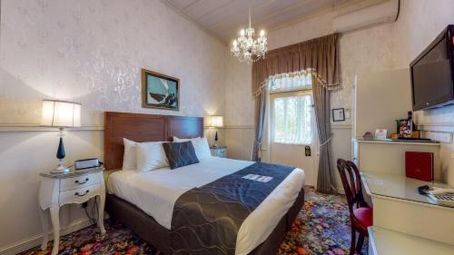 a bedroom with a bed and a desk and a television at Prince's Gate Hotel in Rotorua