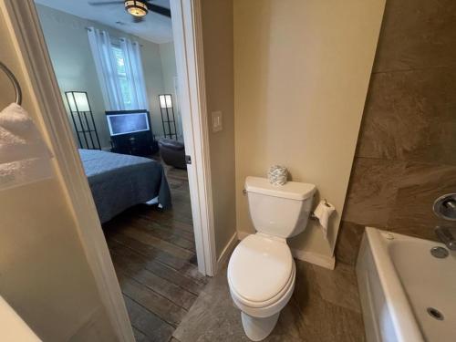 a bathroom with a toilet and a bed and a tub at Suite2-1King Bed1Bath-1BlockFromMercerHospitals in Macon