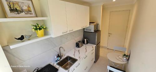a kitchen with white cabinets and a counter top at Be My Guest in Beachlands in Auckland