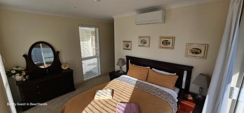 a bedroom with a bed and a mirror at Be My Guest in Beachlands in Auckland