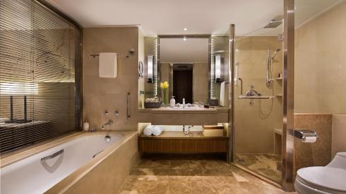 a bathroom with a tub and a sink and a toilet at Marriott Executive Apartments Tianjin TEDA in Binhai