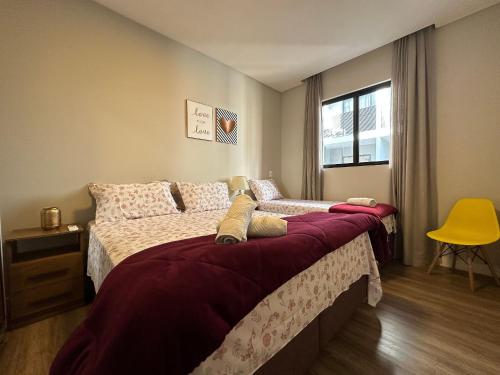 ein Schlafzimmer mit einem Bett und einem gelben Stuhl in der Unterkunft NU01- NOVO | 2 Quartos | Churrasqueira | Garagem in Balneário Camboriú