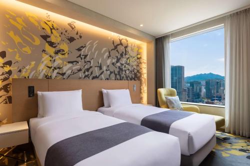two beds in a hotel room with a window at Novotel Suites Ambassador Seoul Yongsan in Seoul
