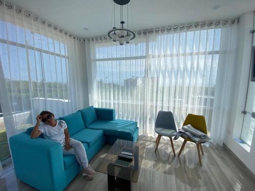 una mujer sentada en un sofá azul en una sala de estar en G&E_BEACH HOUSE, en Mejia