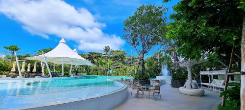 a swimming pool with a table and chairs and an umbrella at Pattaya Seaview Beachfront Skypool Copacabana Jomtien Condo in Jomtien Beach