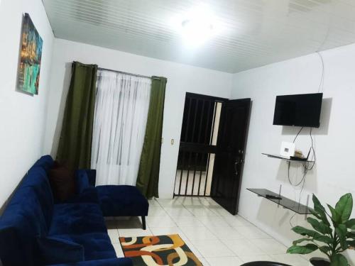 sala de estar con sofá azul y TV en Casa Abundancia, en Aguas Zarcas
