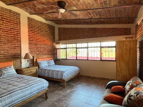 a bedroom with two beds and a brick wall at Casa San Pedro in San Pedro Tesistán