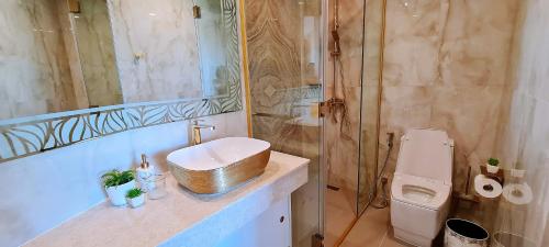 a bathroom with a gold sink and a toilet at Seaview Beachfront Skypool Rooftop Copacabana Jomtien Condo in Jomtien Beach