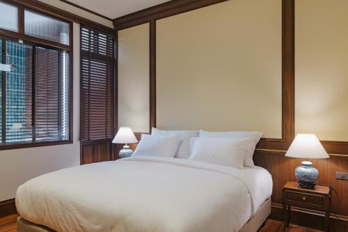 a bedroom with a large white bed with two lamps at Coucou Hotel in Chiang Mai
