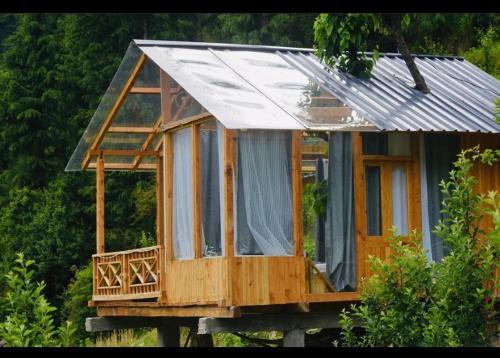 a tiny house with a tin roof on a platform at Cloudwalk Treehouse in Jibhi