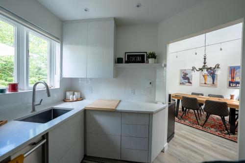 a kitchen with white cabinets and a sink and a table at Le Rétro Chic à Mont-Tremblant in Mont-Tremblant