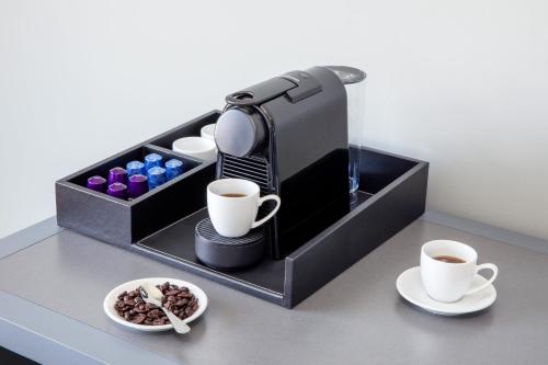 a coffee machine with two cups and a plate of food at Hotel Indigo Flushing - LaGuardia in Queens