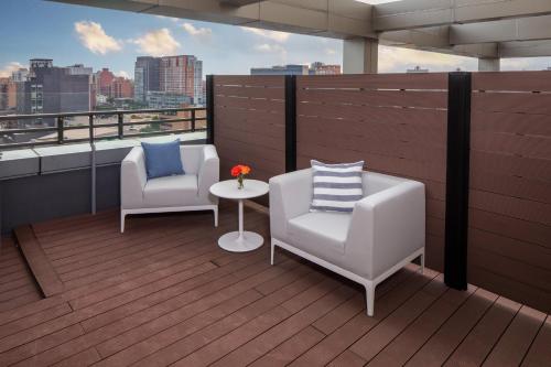 a balcony with two chairs and a table on a roof at Hotel Indigo Flushing - LaGuardia in Queens