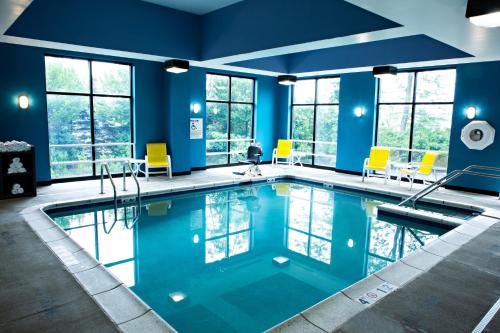 einen Pool in einem Zimmer mit blauen Wänden und gelben Stühlen in der Unterkunft Holiday Inn Express Harrisburg West, an IHG Hotel in Mechanicsburg