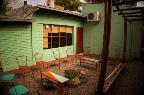 un grupo de sillas y mesas frente a un edificio en Hostel Trotamundos en San Rafael