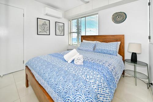 a bedroom with a blue and white bed with a window at Alexandra Headland Ocean Dream - Stunning View ZA6 in Alexandra Headland