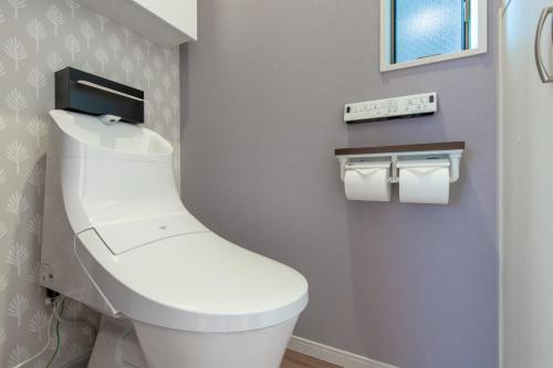 a bathroom with a toilet with a monitor on the wall at Ici Japon Village in Tokyo