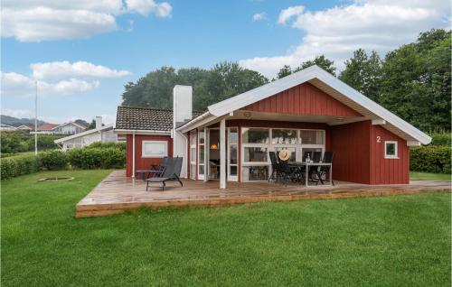 a red shed with a deck in a yard at Three-Bedroom Holiday Home In Sjolund in Sjølund