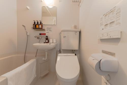a white bathroom with a toilet and a sink at HOTEL R9 The Yard Kasai in Kasai
