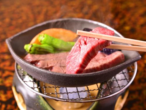 a bowl of meat and vegetables with chopsticks in it at Furuya Ryokan in Atami