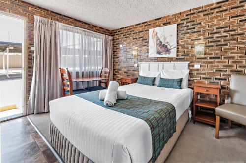 a bedroom with a large bed and a brick wall at Apple & Grape Motel in Stanthorpe