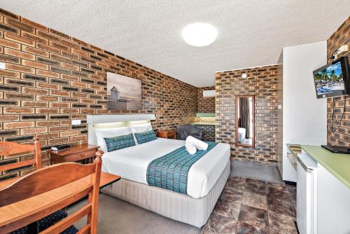 a bedroom with a bed and a brick wall at Apple & Grape Motel in Stanthorpe