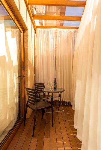 a table and chairs on a balcony with curtains at Casa d'Aroeira Residencial Boutique - Centro de Juqueí - 2 quadras do mar - Serviço de Praia - Roupa de Cama 600 fios algodão Egípcio - Toalhas Banho e Praia - Tudo Novo - Estacionamento Interno - Cozinha - Consulte unidades com Ofurô Hidro e Cromoterapia in Juquei