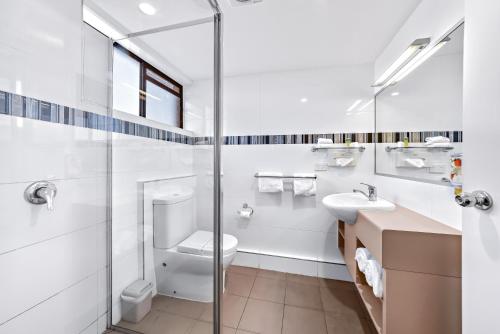 a white bathroom with a toilet and a sink at Apple & Grape Motel in Stanthorpe