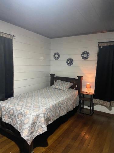 een slaapkamer met een bed en een tafel met een lamp bij Casa Vista Cafe in Cartago